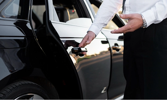 Homem recebendo uma pessoa abrindo a porta traseira do carro